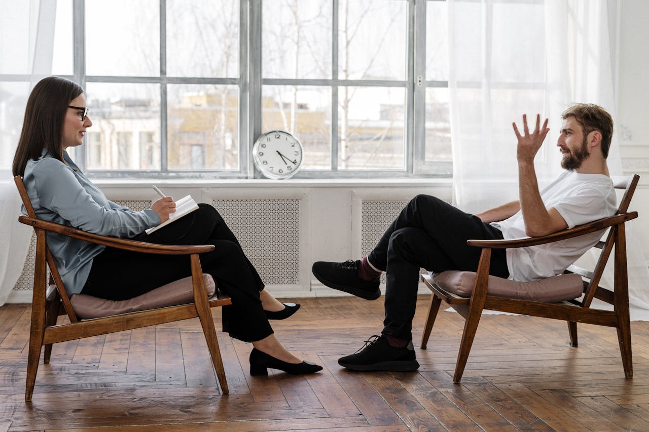 about-01 A therapist engaging in a counseling session with a male patient to support mental health.